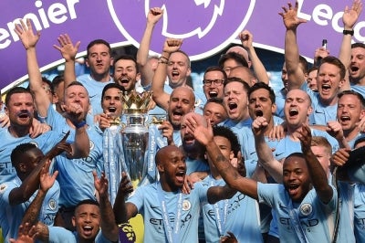 Manchester City's Spanish manager Pep Guardiola (C) holds the Premier League trophy on the pitch with Manchester City players after the English Premier League football match between Manchester City and Huddersfield Town at the Etihad Stadium in Manchester, north west England, on May 6, 2018. (Photo by OLI SCARFF / AFP)