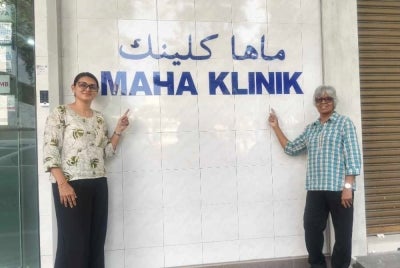 Dr Reshampreet (kiri) dan Mercy menunjukkan nama MAHA Klinik di Alor Setar. 