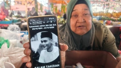 Jamaliah shows a photo of the late Nik Muhamad Adha when met at Changlun permanent Pasar Tani.