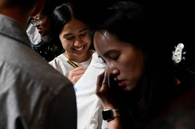 Rising Thai teen rock star Nene Royal (C) signs autographs for supporters following a showcase in Bangkok on Sept 30, 2026. - (Photo by WIKUS DE WET / AFP)