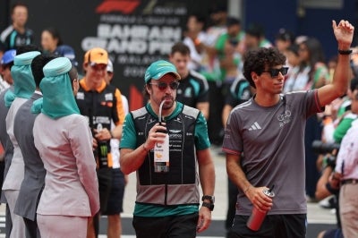 Aston Martin's Spanish driver Fernando Alonso (C) and Audi's Brazilian driver Gabriel Bortoleto (R) arrive for the Driver's Parade ahead of the Formula One Bahrain Grand Prix in Sepang on October 4, 2026. (Photo by I-HWA CHENG / AFP)