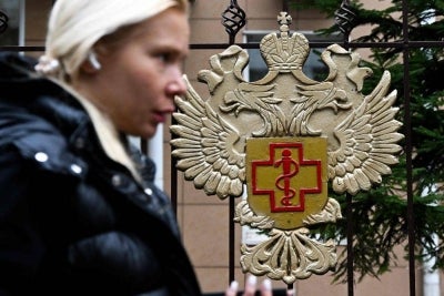 A woman walks past the logo of Russia's consumer and health watchdog Rospotrebnadzor sitting on its grounds' fencing in Moscow. Russian officials downplayed reports that a laboratory technician in Siberia had died of plague, insisting the situation was under control and that post-mortem tests had not found traces of the disease. -AFP Photo