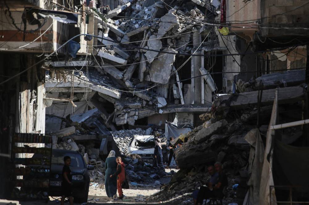 Palestinians walk along a street lined with destroyed buildings at the Jabalia refugee camp in the northern Gaza Strip. Photo by AFP