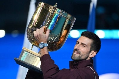 Serbia’s Novak Djokovic holds up the trophy as he celebrates winning the men’s singles final against Australia’s Alex de Minaur at the China Open tennis tournament in Beijing on October 6, 2026. (Photo by GREG BAKER / AFP)
