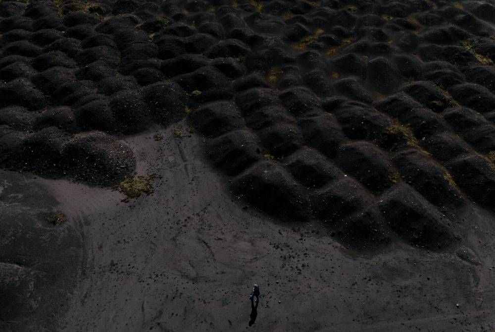 This aerial photo shows a man walking near waste dumps of the metallurgical plant in Elbasan, on March 7, 2025. - (Photo by Adnan Beci / AFP)