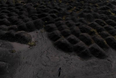This aerial photo shows a man walking near waste dumps of the metallurgical plant in Elbasan, on March 7, 2025. - (Photo by Adnan Beci / AFP)