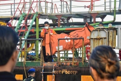 Rescue personnel carry a body bag containing clothes of victims of the Virgo Transport 8 passenger ferry, which capsized Sep 13 carrying 213 passengers and 30 crew while en route from Banjarmasin to Surabaya. AFP FILE PIX