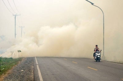 A couple rides a motorcycle through thick haze from forest and land fires in Barito Kuala Regency, South Kalimantan province, on Oct 10. Photo by AFP