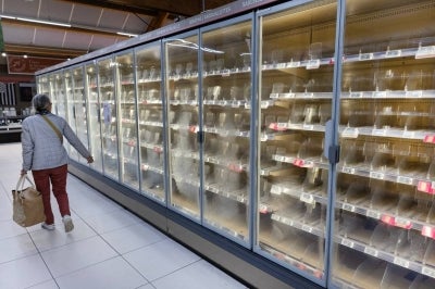 A woman walks past empty fresh-food refrigerators at an Intermarché supermarket in Névez, western France, on Oct 12, 2026, following a cyberattack affecting the French supermarket chains Intermarché and Cooperative U that caused their refrigerators to defrost. - (Photo by FRED TANNEAU / AFP)