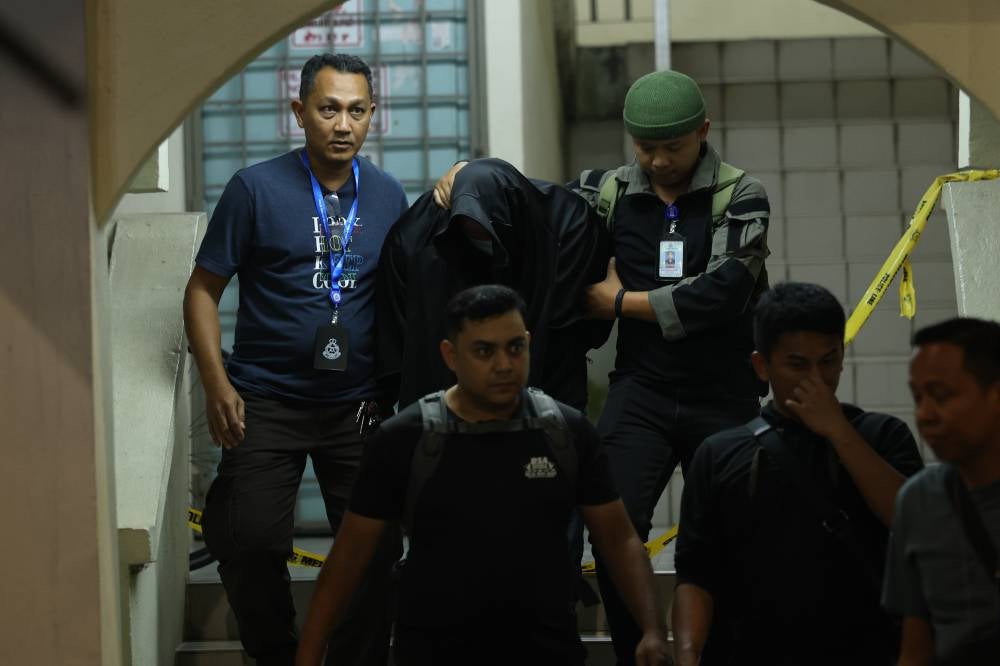 A man believed to be the husband of a Customs officer who was found dead, escorted by police officers near a residence at the Kuala Lumpur International Airport (KLIA) Quarters, last night to assist in investigations. - Photo by Bernama