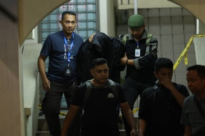 A man believed to be the husband of a Customs officer who was found dead, escorted by police officers near a residence at the Kuala Lumpur International Airport (KLIA) Quarters, last night to assist in investigations. - Photo by Bernama