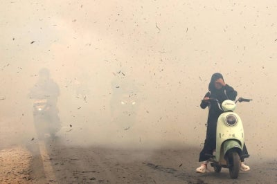 Motorists ride through the smoke of a fire at Sungai Tabuk village in Banjar Regency, South Kalimantan Province on October 16, 2026. Toxic haze has covered parts of Indonesia, Malaysia and Singapore for weeks as Jakarta struggles to contain fires that have scorched large tracts of Borneo and Sumatra, with the smoke drifting across the region. (Photo by MUDA SAGALA / AFP)