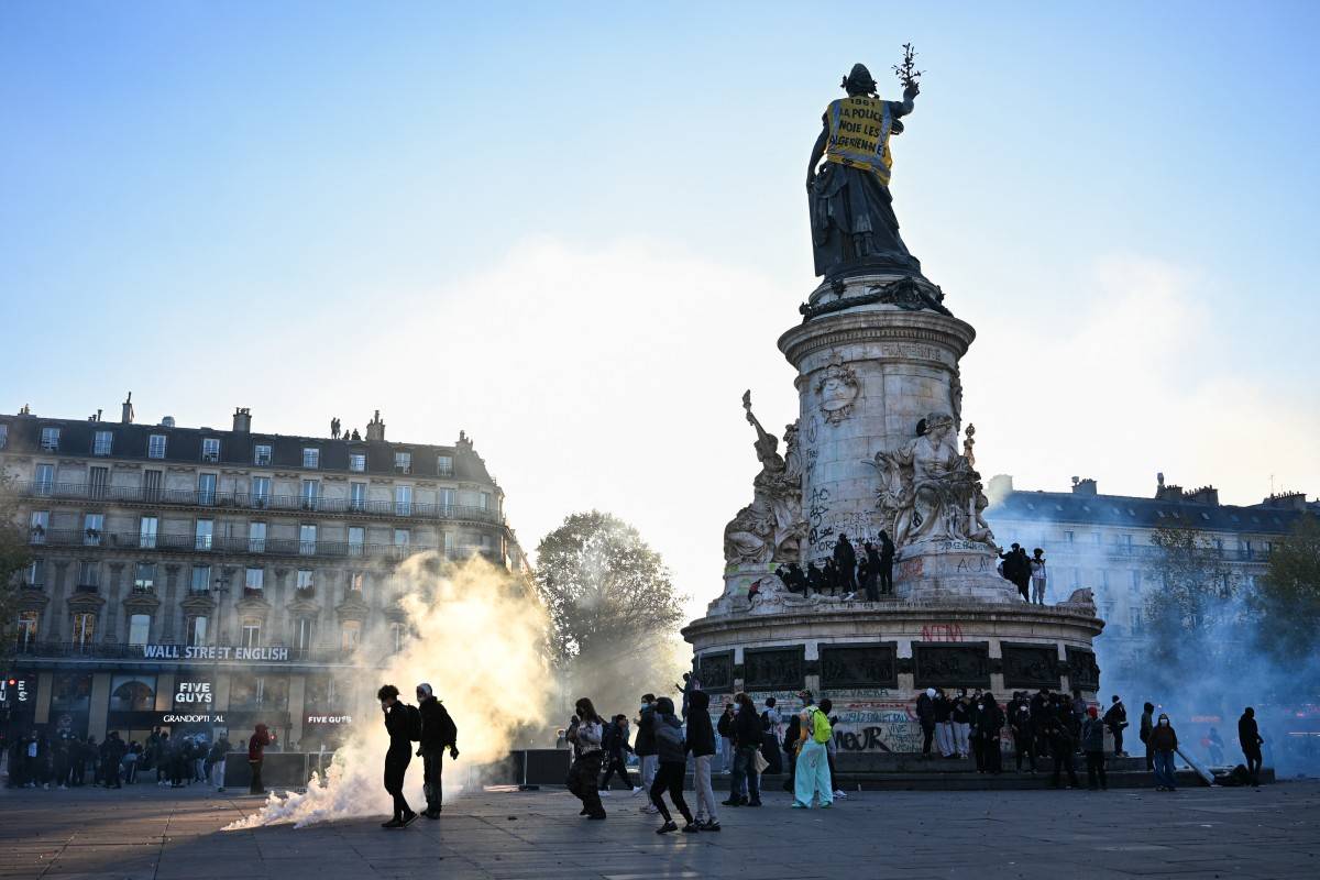Protesters walk next to tear gas and the 'Statue de la Republique' covered with a banner reading "1961 - Police drown Algerians" as they gather during an unauthorised demonstration at Place de la Republique central Paris, on October 18, 2026. (Photo by Matthieu RONDEL / AFP)