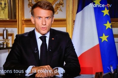 This photograph shows a television monitor broadcasting France's President Emmanuel Macron giving a speech from the Elysee Presidential Palace the day after riots and looting on the sidelines of nationwide protests against the "high cost of living", in Paris on October 18, 2026. (Photo by Ludovic MARIN / AFP)