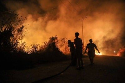 Firefighters work on cointaining a wildfire in Banjarbaru, South Kalimantan province, on October 13, 2026. Toxic haze has shrouded parts of Indonesia, Malaysia and Singapore for weeks as Jakarta struggles to contain fires that have scorched large tracts of Borneo and Sumatra, with the smoke drifting across the region. (Photo by MUDA SAGALA / AFP)