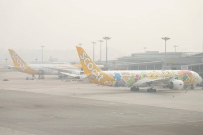 Scoot passenger jets are parked on the tarmac at Changi Airport in Singapore on October 16, 2026, as the country continues to be shrouded in haze caused by fires in Indonesia. Toxic haze has covered parts of Indonesia, Malaysia and Singapore for weeks as Jakarta struggles to contain fires that have scorched large tracts of Borneo and Sumatra, with the smoke drifting across the region. (Photo by Yuichi YAMAZAKI / AFP)