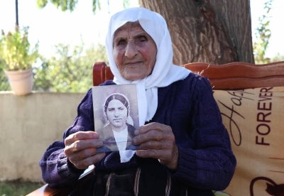 The 117-year-old Qamile Marra holds a black and white photograph from her youth during an interview with AFP in the garden of her home. Photo by AFP
