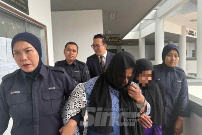 Shofikah (centre) is charged in court for causing hurt to a one-year-old baby last month. - PHOTO: SINAR