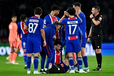 PSG's Georgian forward #07 Khvicha Kvaratskhelia (C) is medically assisted after an injury during the UEFA Champions League first round day 3 football match between Paris Saint-Germain (PSG) and FC Barcelona at the Parc de Princes stadium in Paris on October 20, 2026. (Photo by JULIEN DE ROSA / AFP)