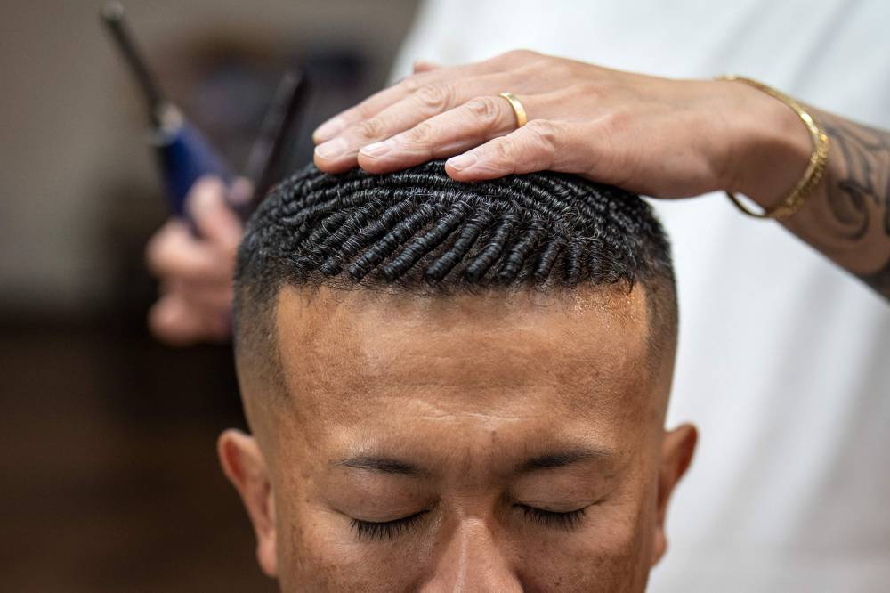 This photo taken on Aug 27, 2026 shows Tekisasu, an active yakuza gangster allied to a major clan, having his hair permed at a barbershop in Tokyo. - (Photo by YUICHI YAMAZAKI / AFP)