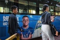 People walk past a bus featuring French football star Kylian Mbappe for Dongpeng Beverage Group's "Bushuila" electrolyte drink on a street in Shanghai. Kylian Mbappe was dropped by major brands in China after a video circulated online in which the French football star apparently joked about former leader Mao Zedong. -AFP Photo