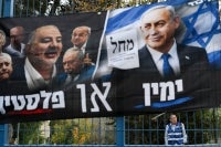 A volunteer stands behind a banner for Israeli Prime Minister Benjamin Netanyahu's Likud party at a polling station in Jerusalem on October 27, 2026, on the day of Israel's legislative election. (Photo by Jewel SAMAD / AFP)
