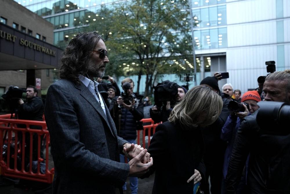 British comedian and actor Russell Brand and his wife Laura leave Southwark Crown Court in south London on Oct 26, 2026. - (Photo by CARLOS JASSO / AFP)