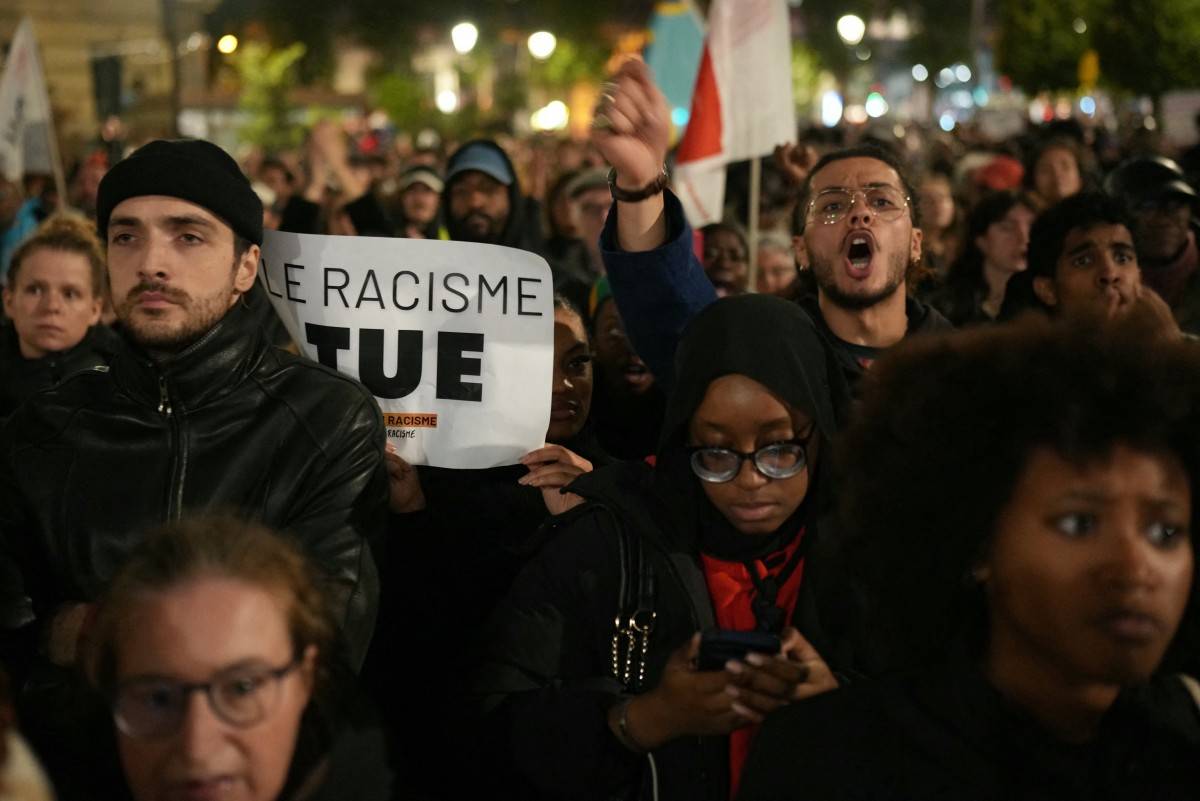 A protester holds a placard reading "Racism kills" during a gathering organised by SOS Racisme and other anti-racism organisations at Place de la Bataille-de-Stalingrad in Paris, on October 26, 2026, to denounce the normalisation of racist hatred and pay tribute to the victims of October 23 deadly shooting in Trappes in the Yvelines region. Marches were held on October 25 in tribute to a man killed in the shooting, Pengo Bossio Wangi, a 26-year-old French national of Congolese origin, and more were planned for today in several French cities, including Paris. (Photo by Dimitar DILKOFF / AFP)