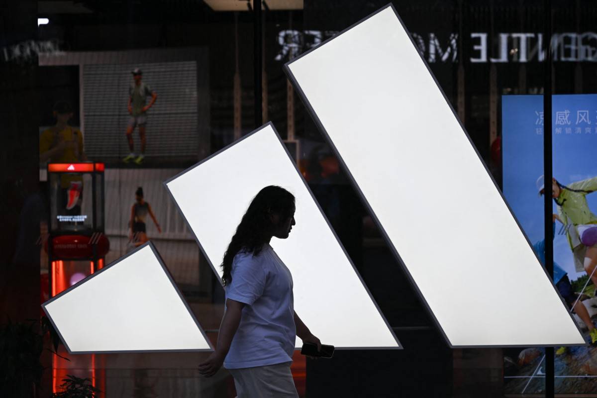 A woman walks past an Adidas store at a mall in Beijing.(Photo by Pedro PARDO / AFP)