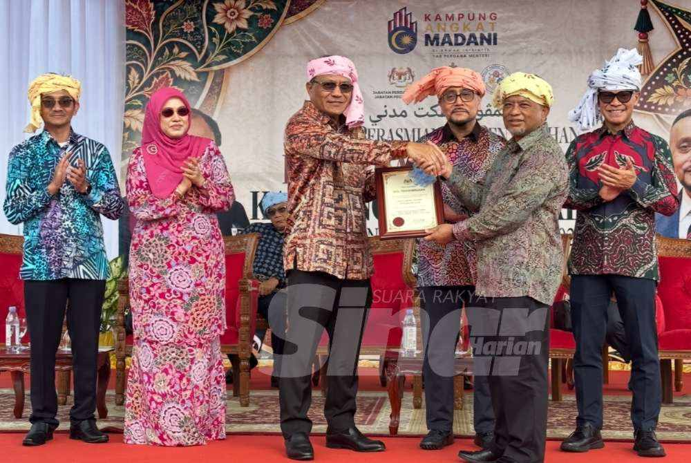 Mohd Dusuki (third from left) presents a symbolic representation of the infrastructure to the Kok Lanas community. - Photo by ADILA SHARINNI WAHID