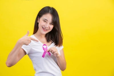 Breast cancer month, a woman in a white T-shirt with a satin pink ribbon on her chest, a symbol for breast cancer awareness campaign in October