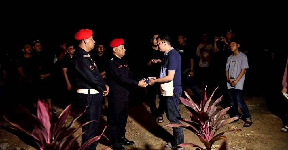 Pegawai Penjaga Trup FRU Unit 5, Sungai Senam, Asisten Superintendan Yamin Mat Zaid (tengah) menyerahkan Jalur Gemilang kepada adik kandung Allahyarham Sarjan Mohd Roslan Abd Rahim, Mohamad Hazizi Abd Rahim,