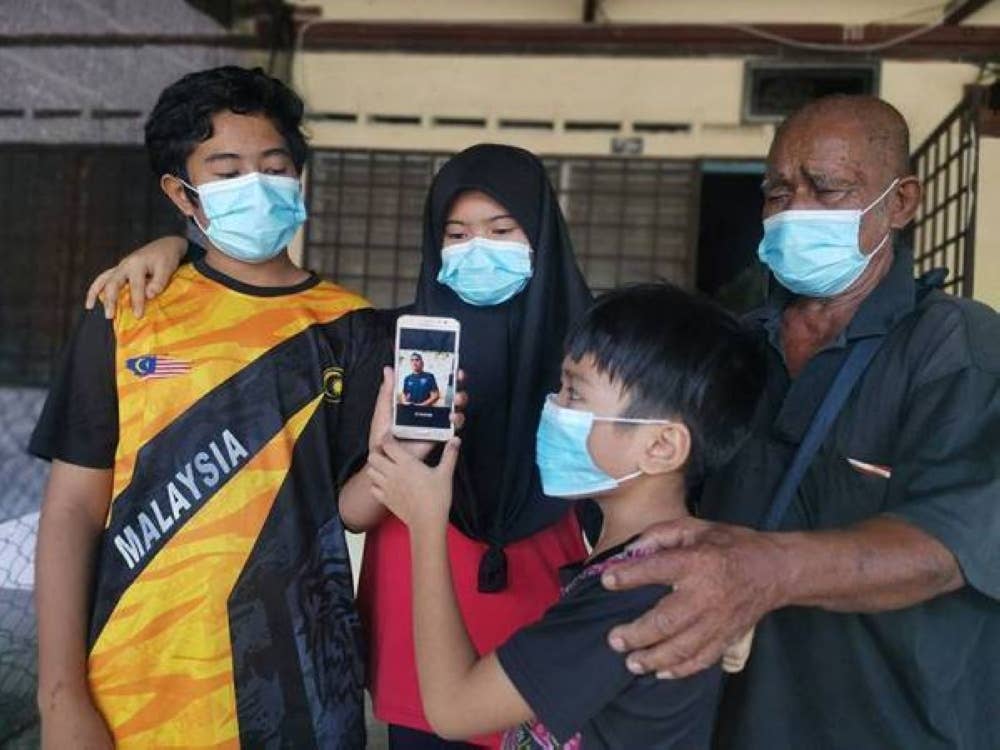 Said (kanan) dan tiga cucunya menunjukkan gambar Shahrul Nizwan