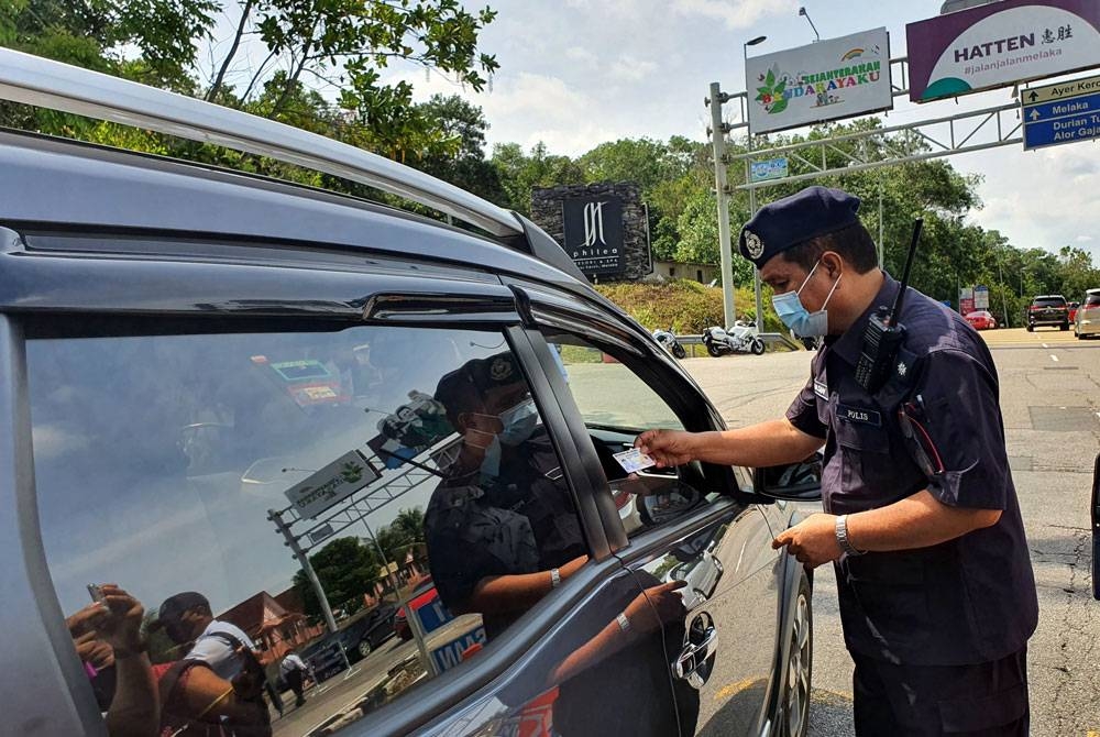 Anggota polis memeriksa lesen pemandu pada Op Selamat 17 sempena sambutan Tahun Baharu Cina 2022 di Tol Ayer Keroh, Melaka pada Rabu.