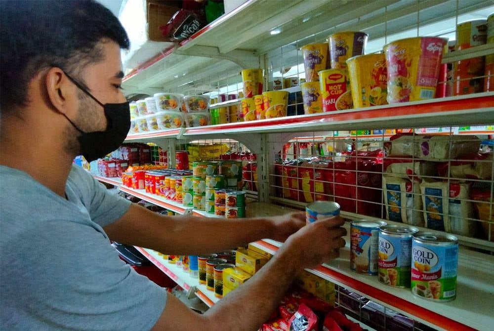 Arman menyusun beberapa produk makanan dalam tin untuk dijual kepada pembeli.