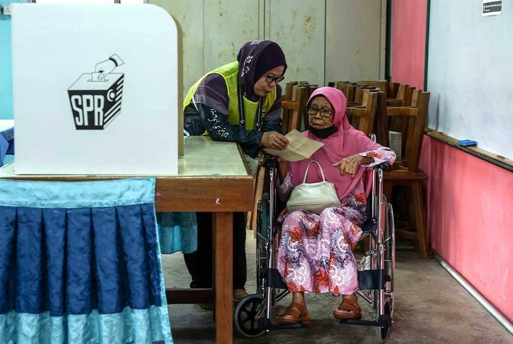 Petugas SPR membantu warga emas, Zauyah Sulaiman, 84, melakukan proses mengundi di Pusat Mengundi
Sekolah Kebangsaan Pontian, Rompin.