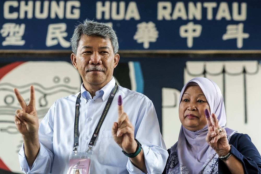 Mohamad bersama Raja Salbiah menunjukkan jari yang dicelup dakwat kekal mengundi pada PRN
di SJKC Chung Hua di Rantau pada Sabtu.