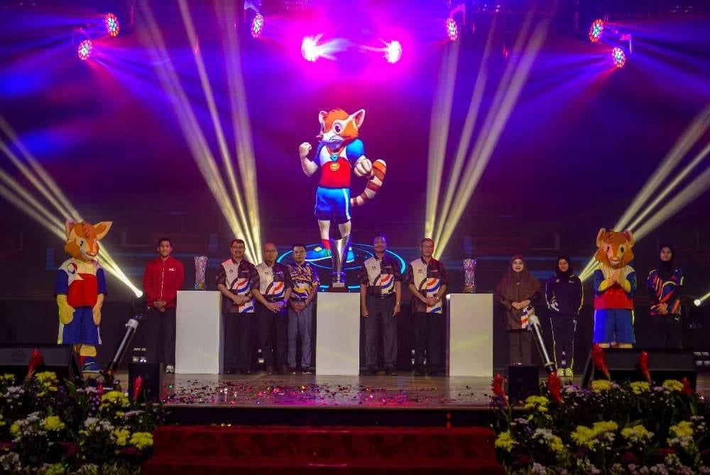 Mohd Nor Azman (tengah) bergambar bersama maskot Sukan Institusi Pendidikan Tinggi (SUKIPT) dan tiga piala utama SUKIPT selepas merasmikan Majlis Pelancaran SUKIPT 2026 di Dewan Tunku Canselor Universiti Malaya pada Selasa.