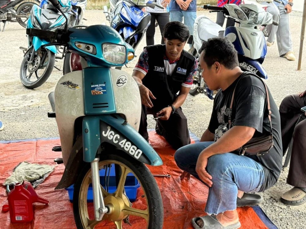 Mahasiswa UTeM berkongsi pengetahuan berkaitan penyelenggaraan asas motosikal kepada penduduk setempat sempena Program UTeM@KPT Prihatin di Kampung Nelayan, Parit Jawa, Johor.