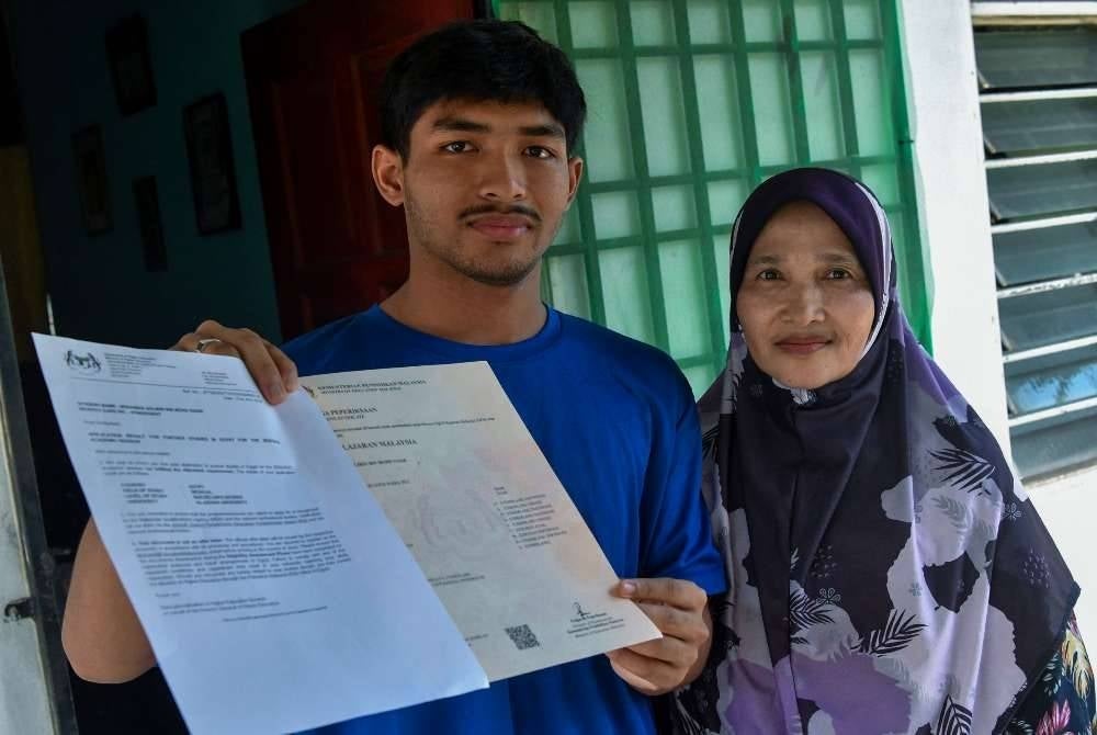 Bekas pelajar Maktab Rendah Sains MARA (MRSM) Jeli, Mohamad Solihin Mohd Nasir, 19, (kiri) ditemani ibunya, Faridah Mohamad, 60, menunjukkan surat tawaran pengajian dan Sijil Pelajar Malaysia (SPM) ketika ditemui pemberita di Kampung Kubang Keranji, Pasir Tumboh.