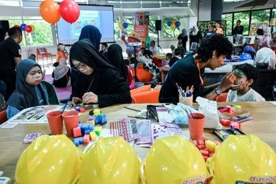 Penuntut Ijazah Sarjana Muda Produksi Animasi 2D Universiti Teknologi MARA Nur Farina Izzatul Daur, 23 (dua, kiri) dan penuntut Diploma Animasi 3D Kolej Vokasional Kluang, Muhammad Danish Ahlami Imtiaz Alam, 20, (dua, kanan) melukis wajah pelanggan ciliknya selepas tayangan eksklusif siri animasi terbaharu Build-It Blocks.