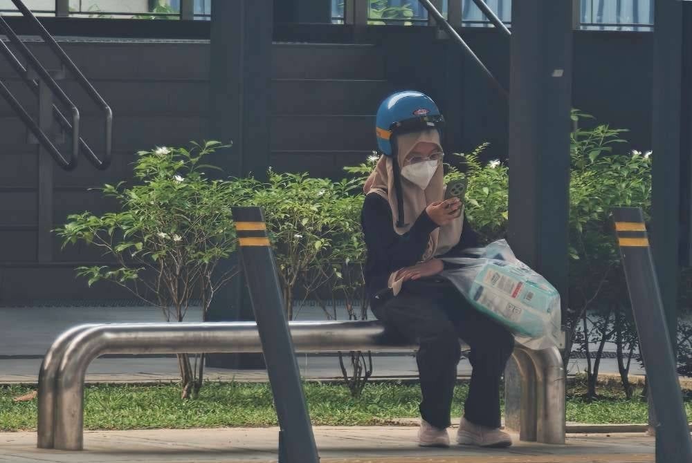 Seorang wanita memakai pelitup muka bagi mengurangkan pendedahan kepada jerebu ketika berada di kawasan terbuka di Kuala Lumpur. - Foto Bernama