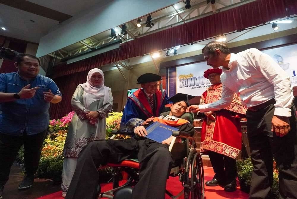Muhammad Afiq Mohd Hairul Fahmy ditemani ibu bapanya ketika menerima Ijazah Sarjana Muda Teknologi Maklumat dengan Pengurusan Perniagaan (Kepujian) pada Konvokesyen UC TATI ke-26.