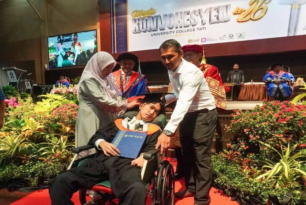 Muhammad Afiq Mohd Hairul Fahmy ditemani ibu bapanya ketika menerima Ijazah Sarjana Muda Teknologi Maklumat dengan Pengurusan Perniagaan (Kepujian) pada Konvokesyen UC TATI ke-26.