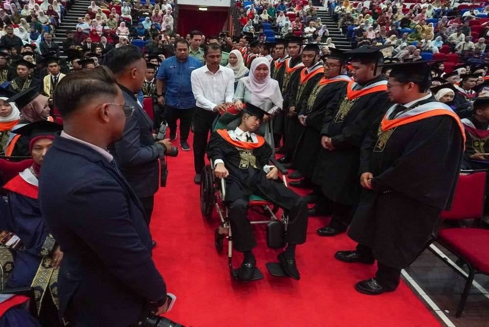 Muhammad Afiq Mohd Hairul Fahmy ditemani ibu bapanya ketika menerima Ijazah Sarjana Muda Teknologi Maklumat dengan Pengurusan Perniagaan (Kepujian) pada Konvokesyen UC TATI ke-26.
