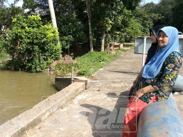 Che Nab (kanan) dan cucunya melihat aliran limpahan air Sungai Golok yang membanjiri kawasan rumahnya di Kampung Siram.