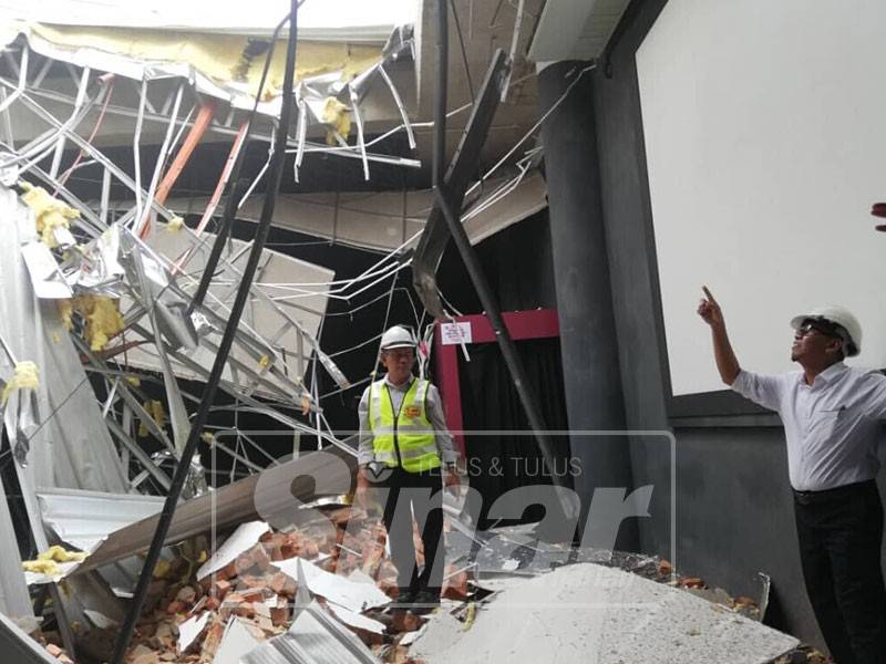Mohd Sofi (kanan) ketika melihat dinding Planetarium Melaka yang runtuh.