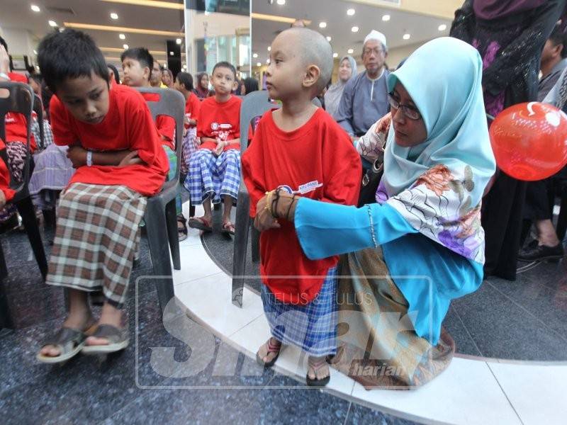 Ibunya, Nurul Akma Jamil sedang membetulkan kain Muhamad Isyraf sebelum proses berkhatan dimulakan.