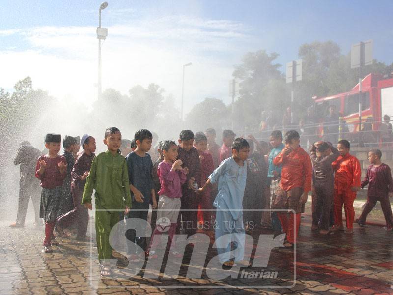 Kanak-kanak dimandikan dengn semburan air daripada pasukan bomba.