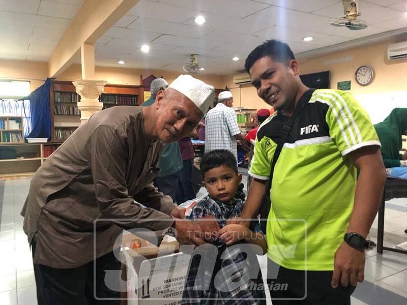 Abdul Wahab menyerahkan duit 'merah' kepada kanak-kanak yang selesai berkhatan.